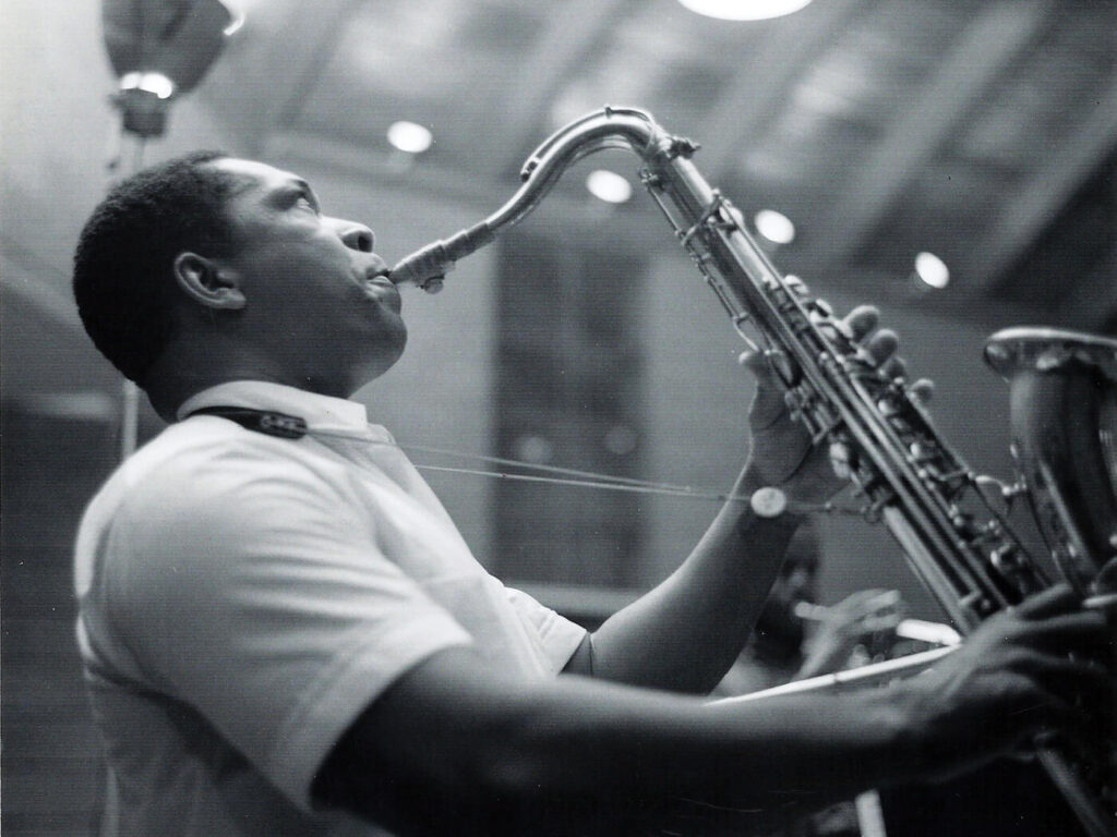 John Coltrane holding his saxophone, photographed by Chuck Stewart