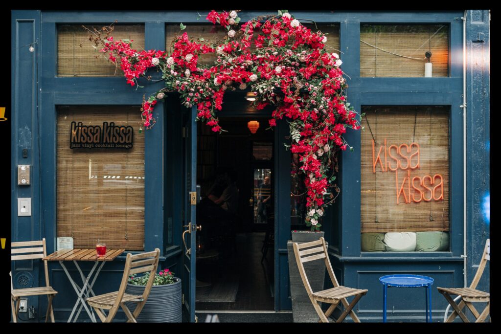 The Kissa Kissa storefront on Franklin Avenue in daylight, blue facade and sidewalk tables