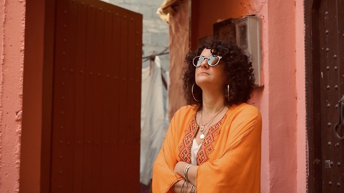 Laura Elkeslassy standing in a doorway in Marrakech’s mellah (Jewish quarter) wearing an orange kaftan
