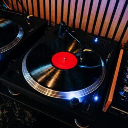 Two turntables behind the bar at Kissa Kissa, one playing a red-label LP with a yellow-lift Ortofon cartridge, beside the R2 rotary mixer